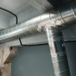 Des tuyaux de ventilation en argent suspendus au plafond à l'intérieur du bâtiment